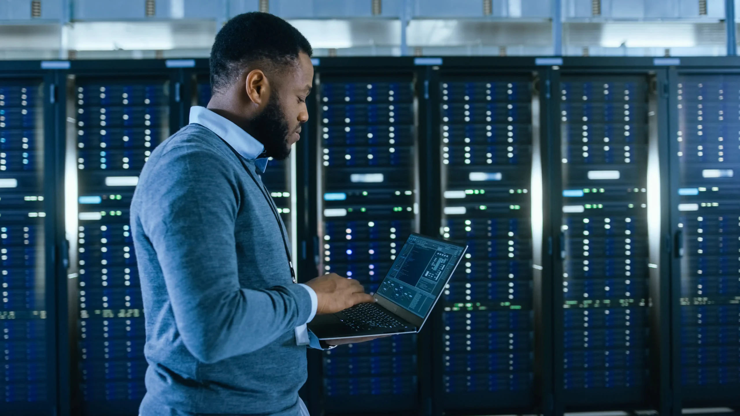 Man on his laptop in a data center room.