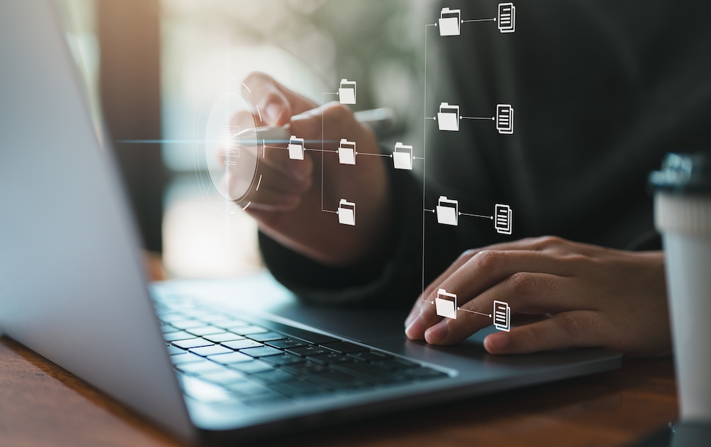 Close-up of a person using a laptop with digital document folders and files appearing on screen, illustrating the concept of streamlined document management and automation