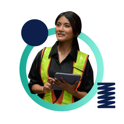 A woman wearing a construction vest and holding a tablet while on a job site.