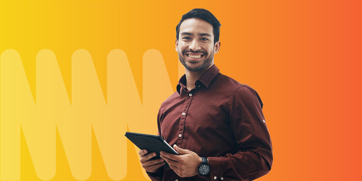 A man holding a tablet in a burgundy shirt, standing in front of an orange and yellow gradient background.