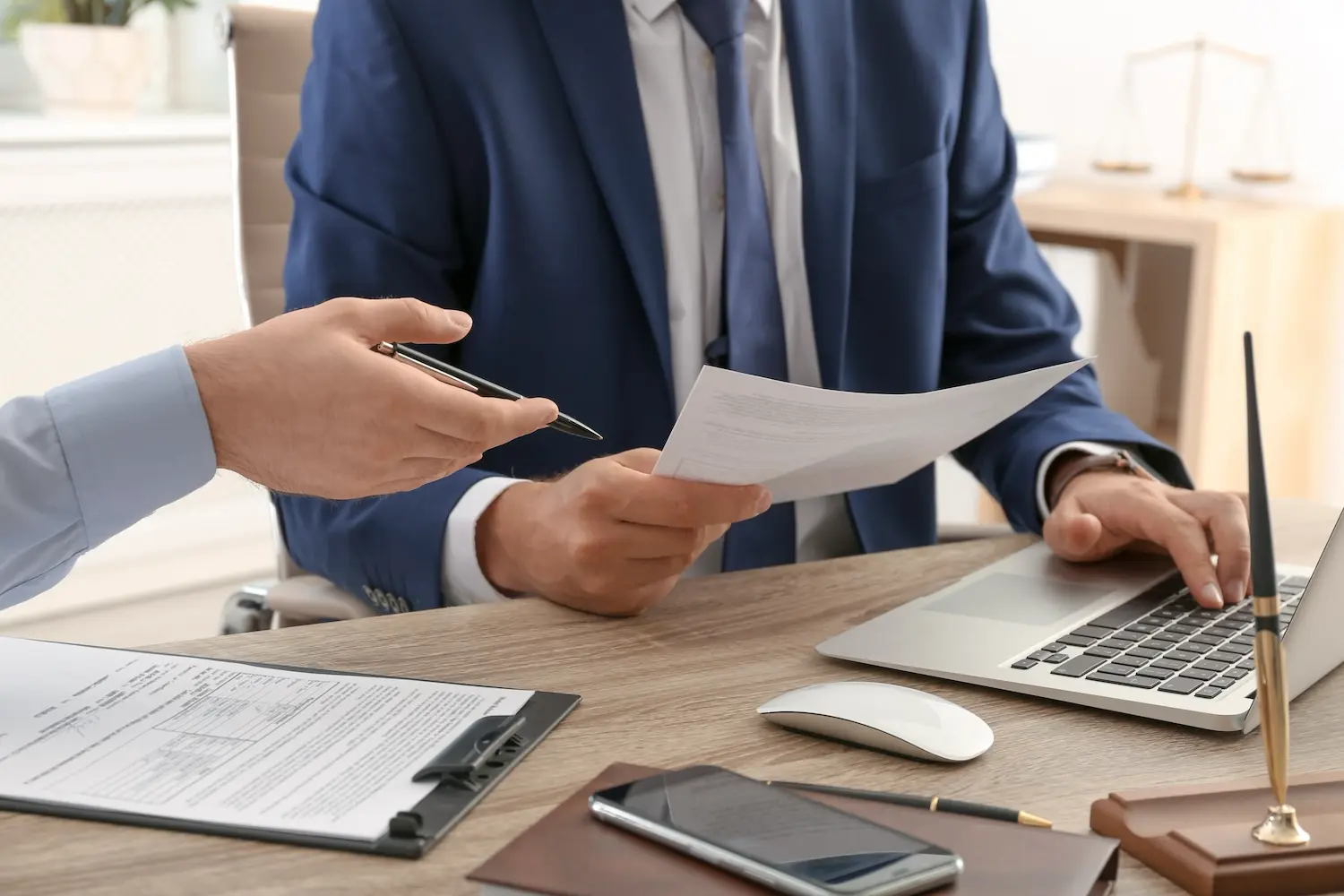 Two professionals in a formal office setting reviewing documents and working on a laptop, representing efficient document management and automation in government and public sector operations