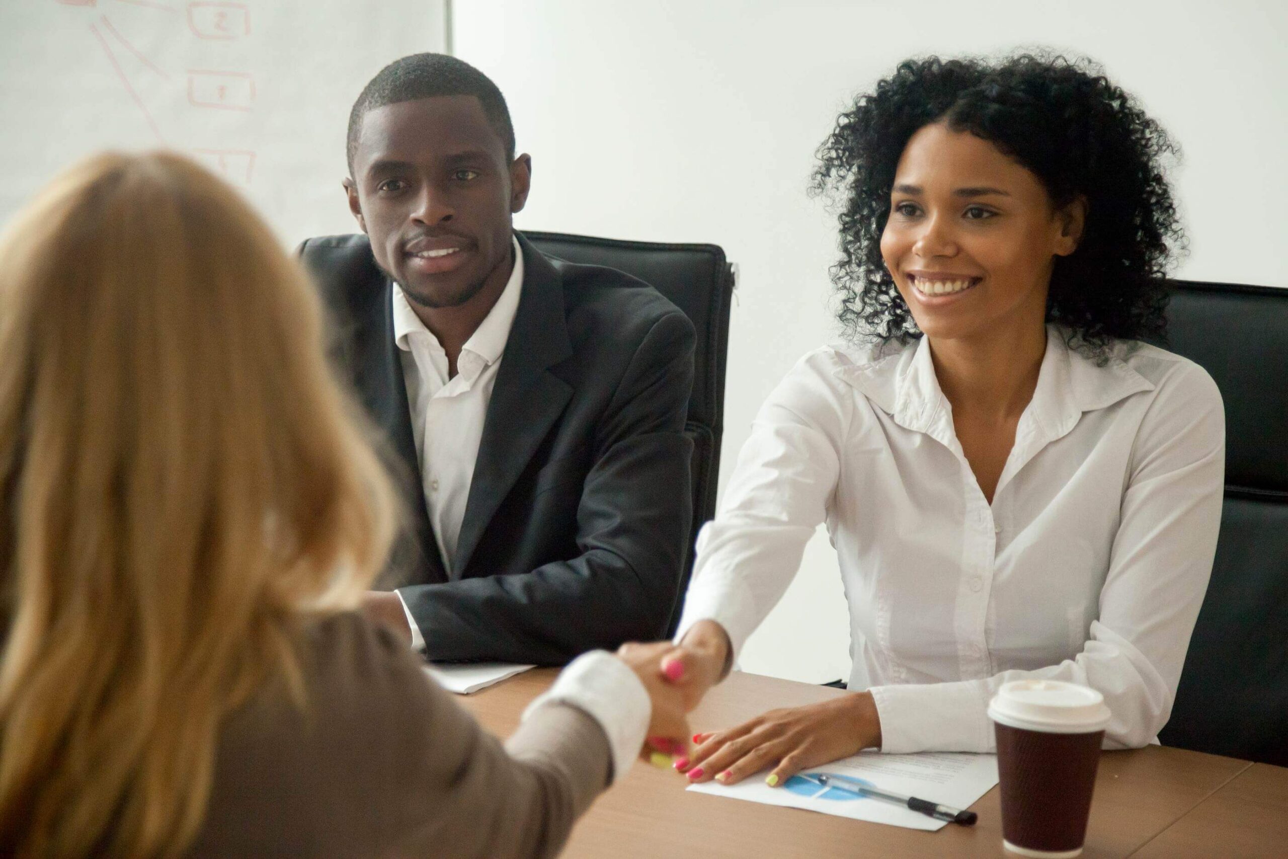 Two business professionals smiling and shaking hands with a client, representing successful sales interactions and enhanced customer engagement through efficient document automation.