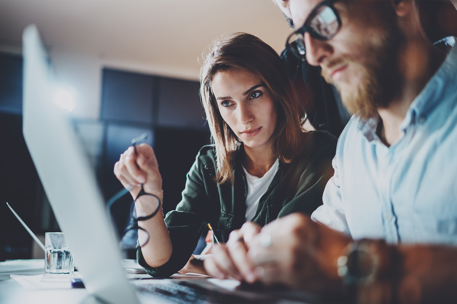 Two professionals collaborating and analyzing data on a computer, representing the benefits of using CPQ software for efficient sales processes and accurate quoting