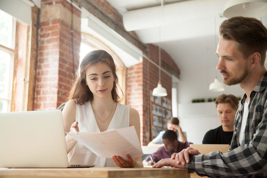 Two professionals collaborating in a modern office setting, reviewing documents and discussing content management strategies, illustrating the benefits of ECM solutions for small and medium-sized businesses.