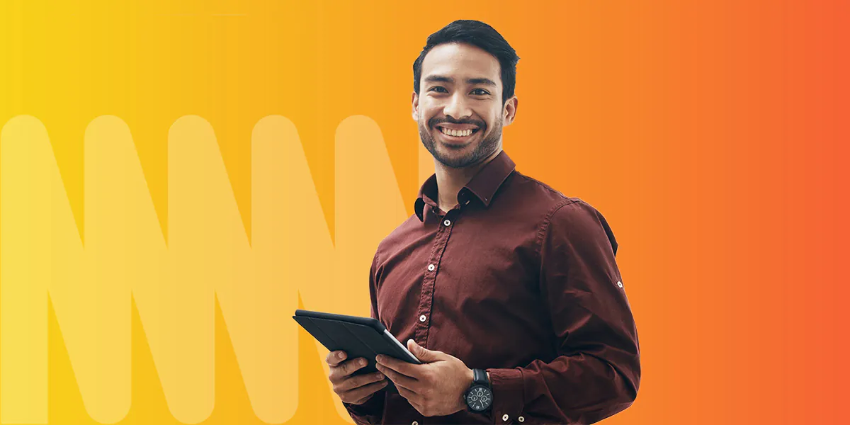 A man holding a tablet in a burgundy shirt, standing in front of an orange and yellow gradient background.