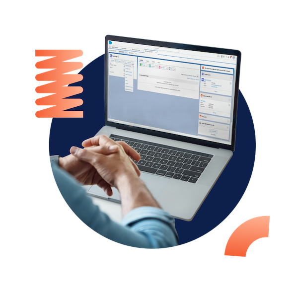 A business woman smiling and writing on a document while working at her desk on a laptop, all placed inside of a designed green circle.