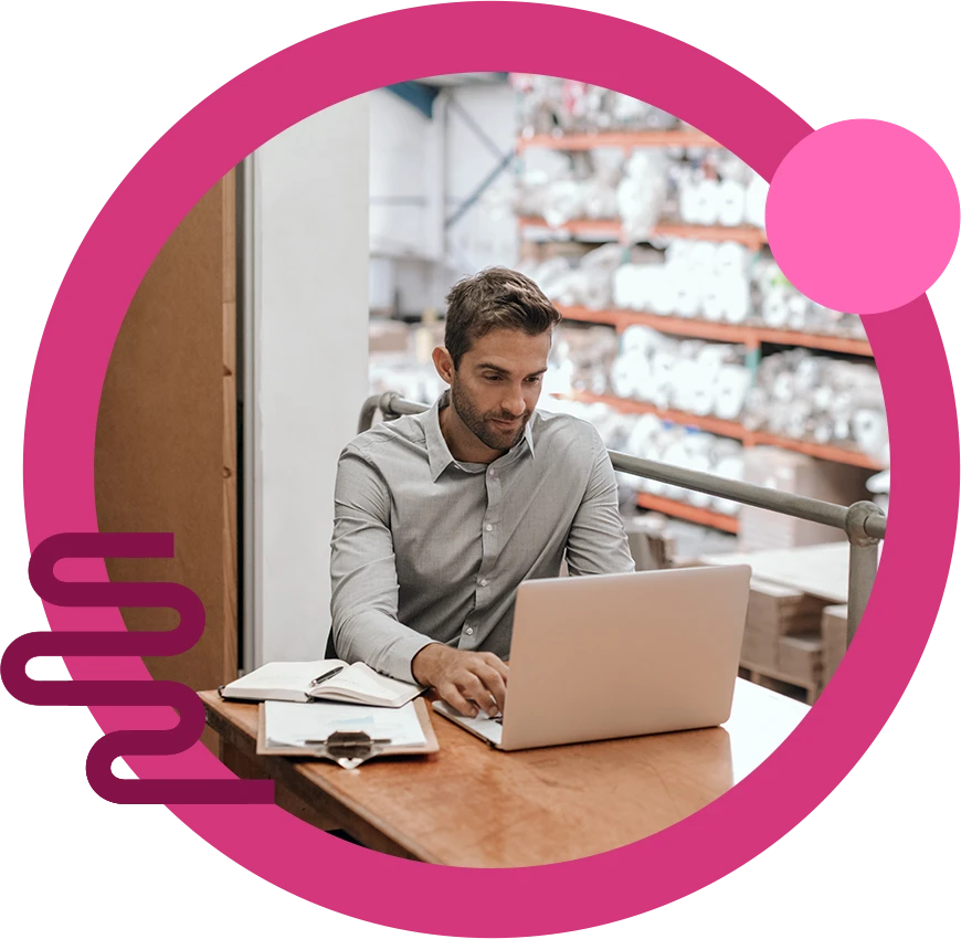 An elderly gentleman on a device in a warehouse.
