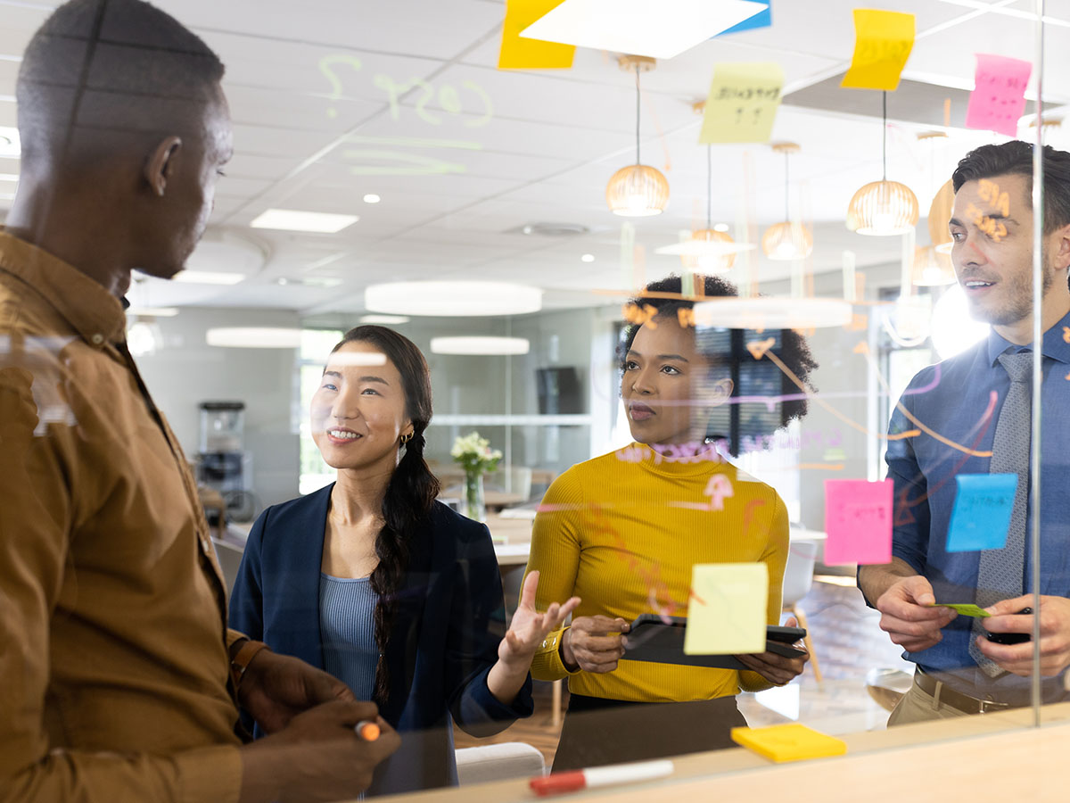 Communicate-with-Citizens-via-Omni-Channel-Documents A group of coworkers discussing in a conference room with post it notes.