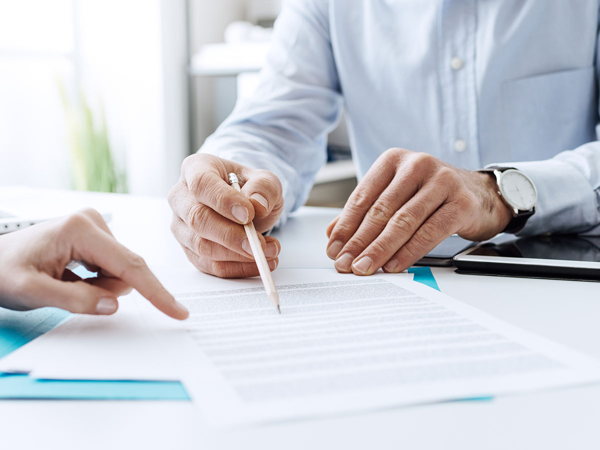 Considerations-for-Insurance-Carriers-to-Modernize-Document-Automation-Processes Pointing to a document on a desk.