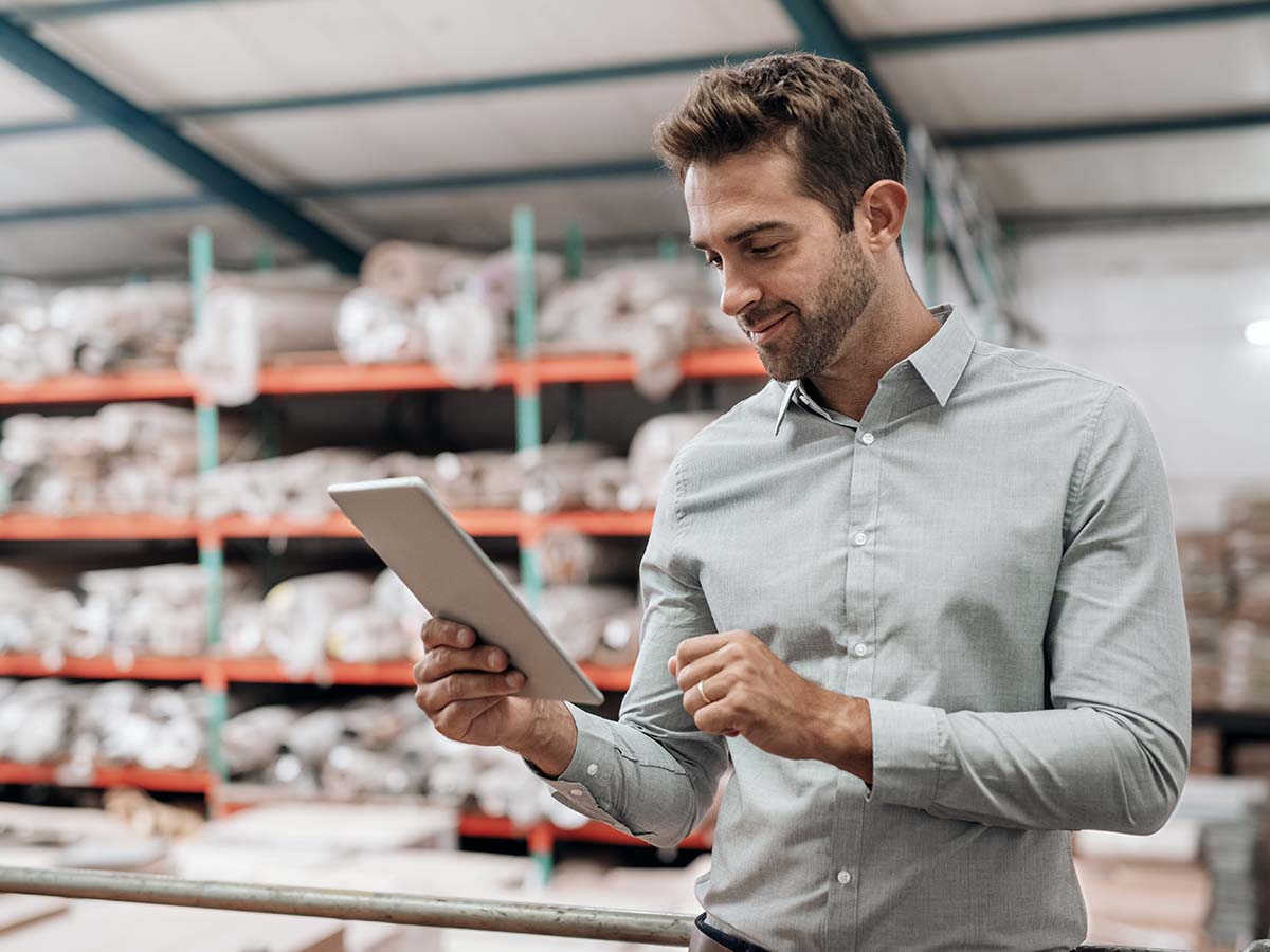 Four-Ways-a-Document-Generation-Solution-Can-Help-Overhaul-Your-Documents A man looking at a tablet in a warehouse.