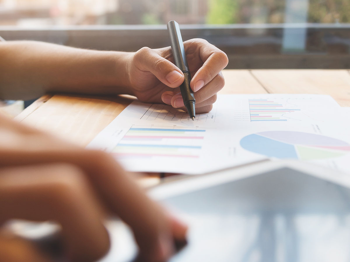 Leverage-Data-and-Automation-to-Optimize-Your-Insurance-Underwriting-Processes A person writing on a chart and using a tablet.