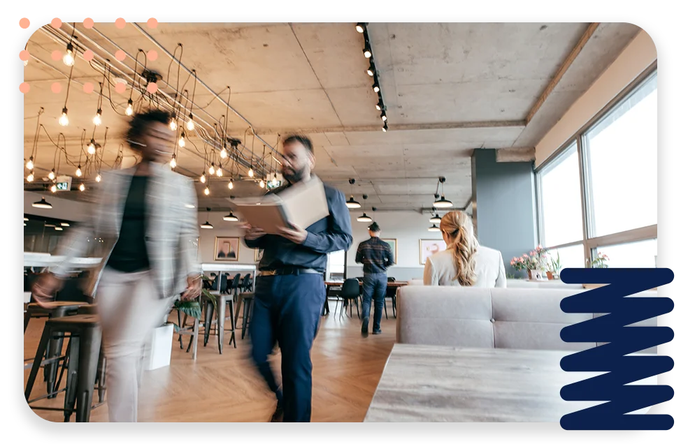 CPQ-Photo-with-two-patterns-three-modules2 An office with cool lighting and business coworkers sitting at a table in a meeting.