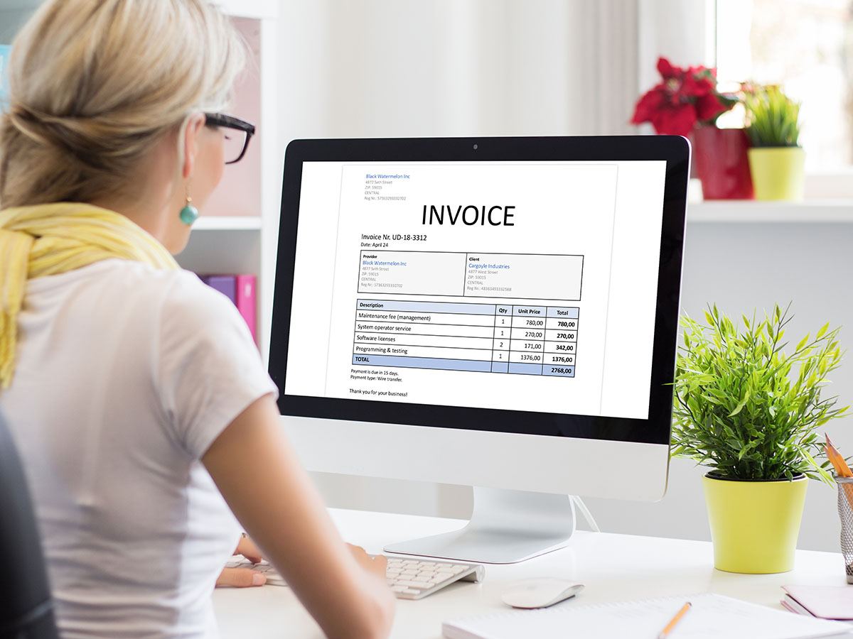 The-Benefits-of-Personalized-Invoices-and-Automated-Integrated-Technologies A woman looking at an invoice on a Mac.