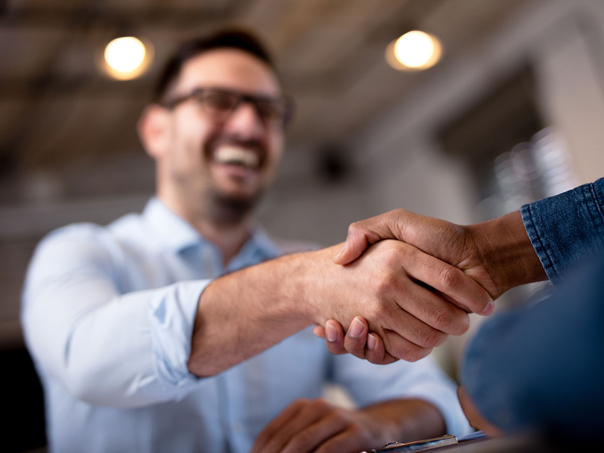 Win-More-Business-Over-Competition-with-CPQ A man and colleague or partner shaking hands and smiling.