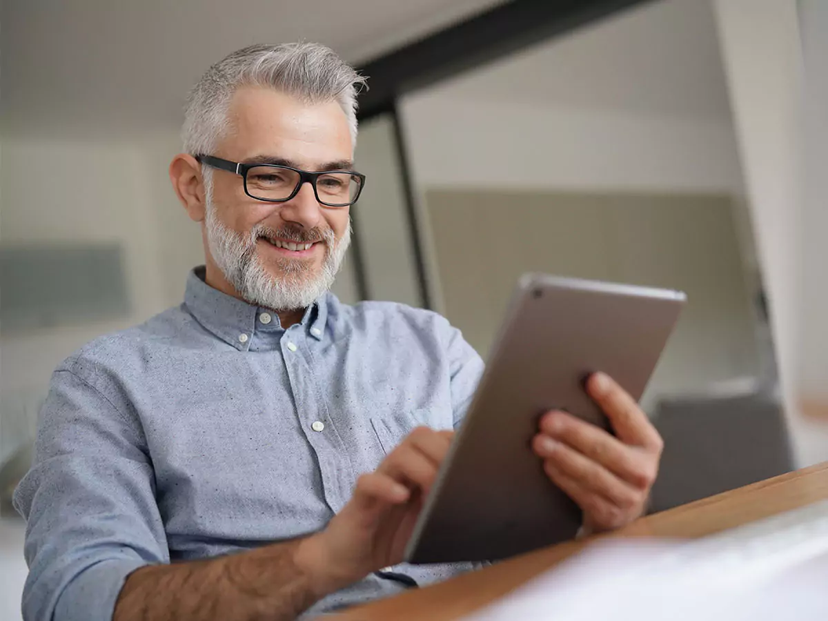 no-more-standalone-systems-featured-image A senior man smiling and using an iPad.
